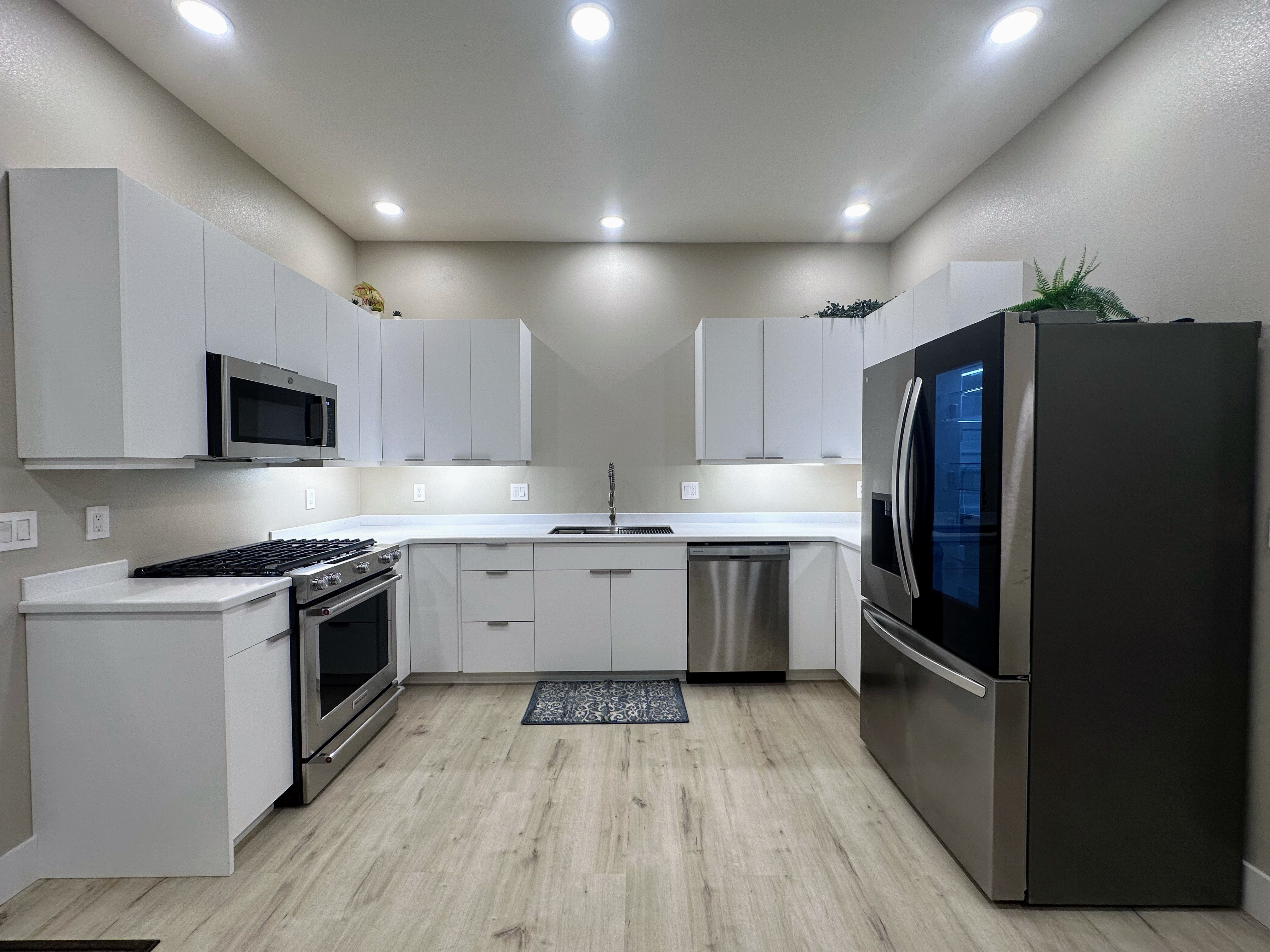 Bright white kitchen around a large window with tall storage towers.